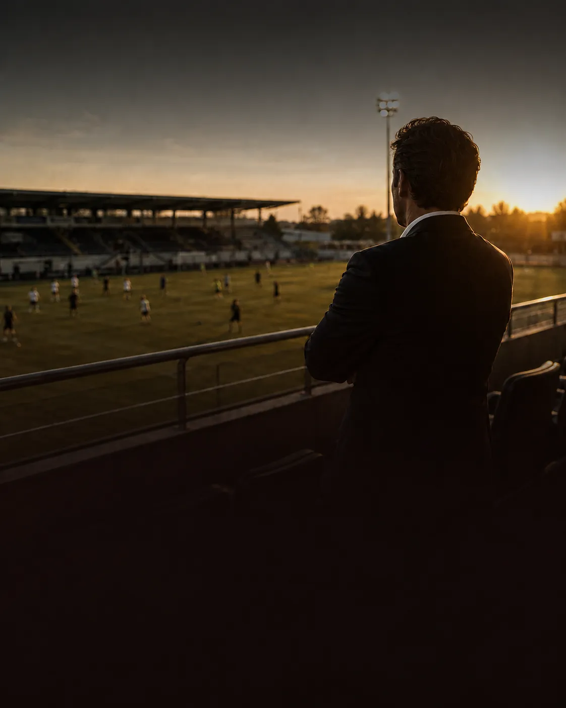 Agent en costume regardant un match au coucher du soleil